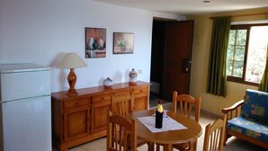 A compact kitchen with a refrigerator, wooden cabinets, a dining table with chairs, and a sofa. - Quiet apartment with sea views (Agulo)