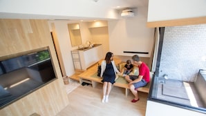 Una cocina moderna con estufa integrada, una zona de comedor con banco y un amplio ventanal con vistas al exterior.