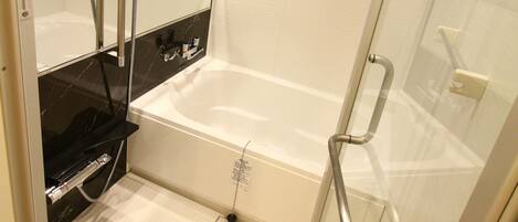A modern bathroom with a glass-enclosed shower, a white bathtub, and a black marble wall.