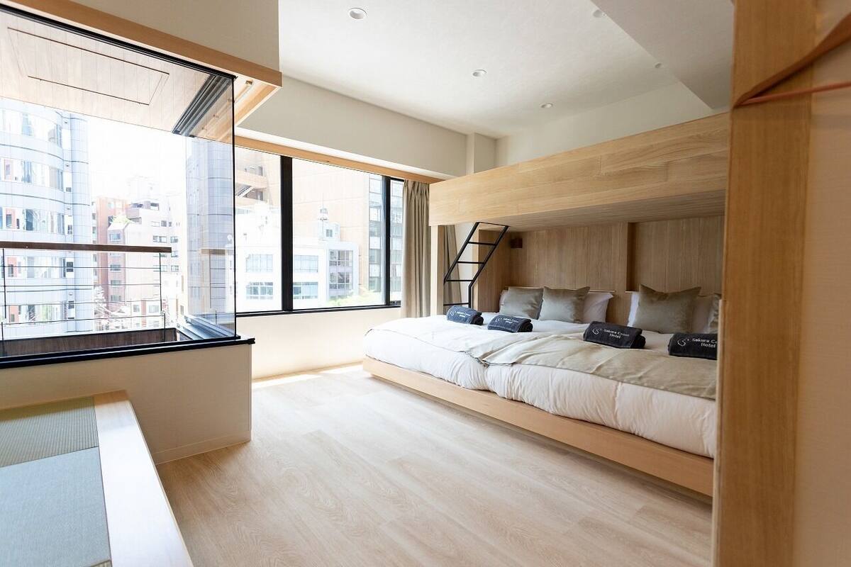 Un dormitorio moderno con cama empotrada, una ventana con vistas a edificios y techo de madera.