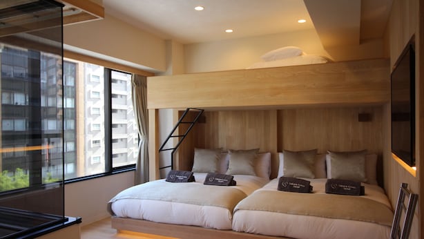 Una habitación de hotel moderna con literas, un ventanal y vistas a un edificio de gran altura.