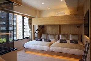 Ein modernes Hotelzimmer mit Etagenbett, großem Fenster und Blick auf ein Hochhaus.