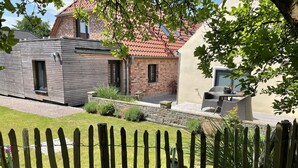 A modern house with a wooden exterior, a brick section, and a patio with outdoor furniture.