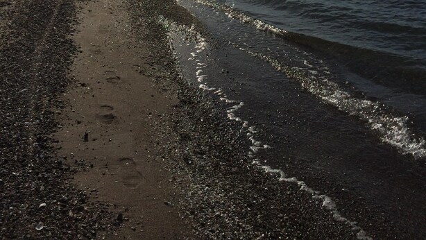 A beach with pebbles and a clear view of the water.