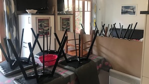 Una sala de estar con televisión, chimenea y comedor con sillas y una mesa.