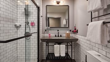 A modern bathroom with a glass shower enclosure, a black sink vanity, and a large mirror above the sink.