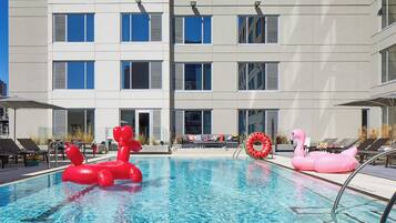 Una piscina al aire libre, sombrillas, sillones reclinables de piscina