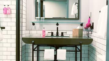 A bathroom with a black sink, white tiles, a mirror, and a towel rack.