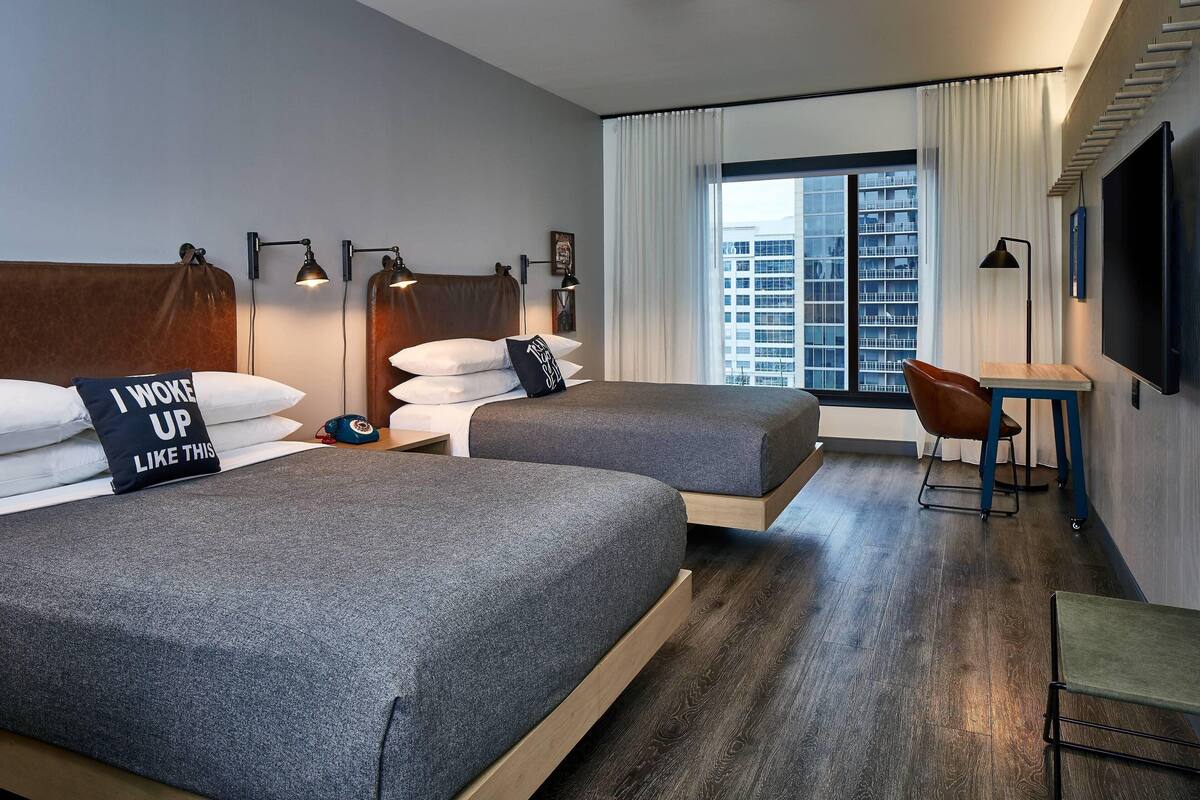 Una habitación de hotel con dos camas, un escritorio, una silla y un televisor.