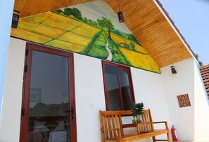 A building with a large window, a wooden bench, and a mural on the wall.