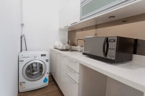 A compact kitchen with a microwave, a washing machine, and a small countertop. - 3r2b Bkt Bintang KL Town City by SYNC (Kuala Lumpur)