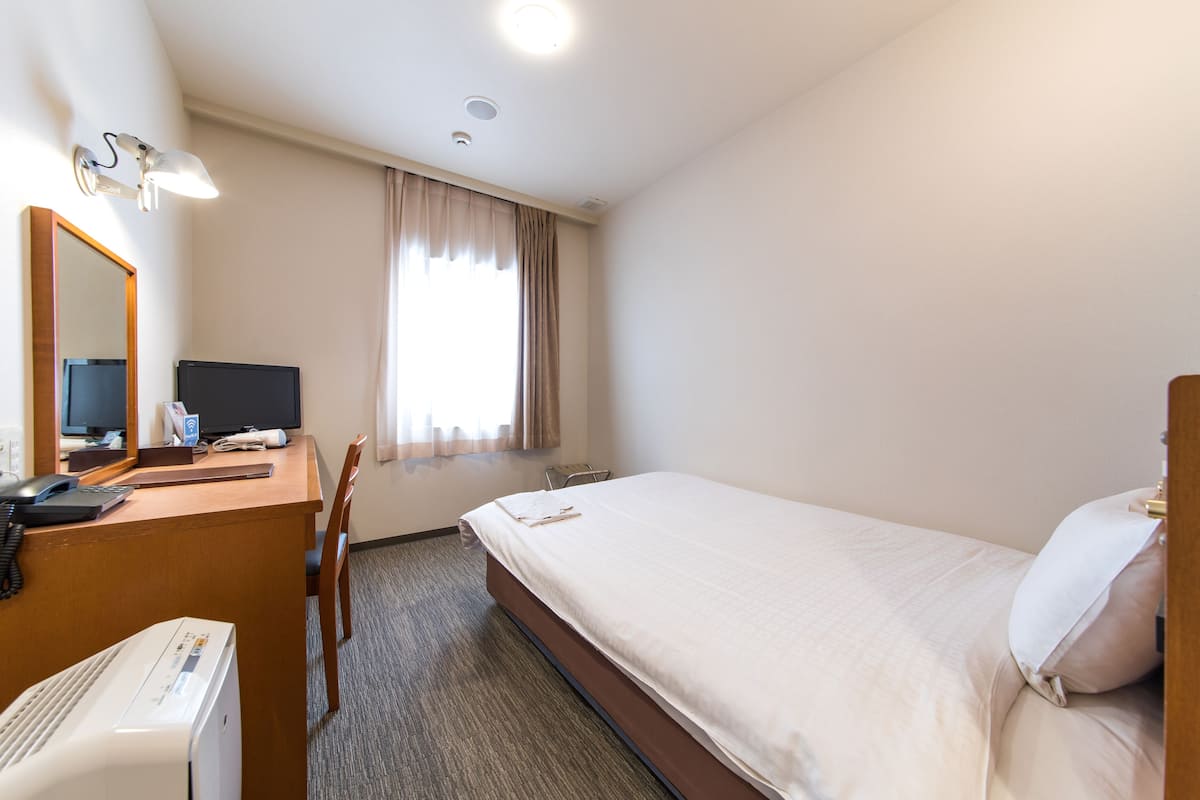 Une chambre d’hôtel équipée d’un lit, d’un bureau, d’une chaise et d’un téléviseur.