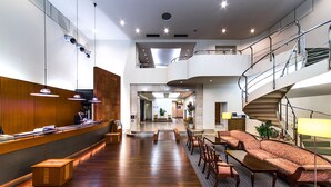 Un vestíbulo amplio con mostrador de recepción, zona de estar y una escalera que conduce a los pisos superiores.