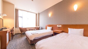 Una habitación de hotel con dos camas, un escritorio, una silla y una ventana con cortinas.