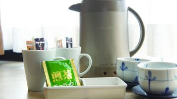 A tea set with a kettle, cups, and a tea packet on a table.