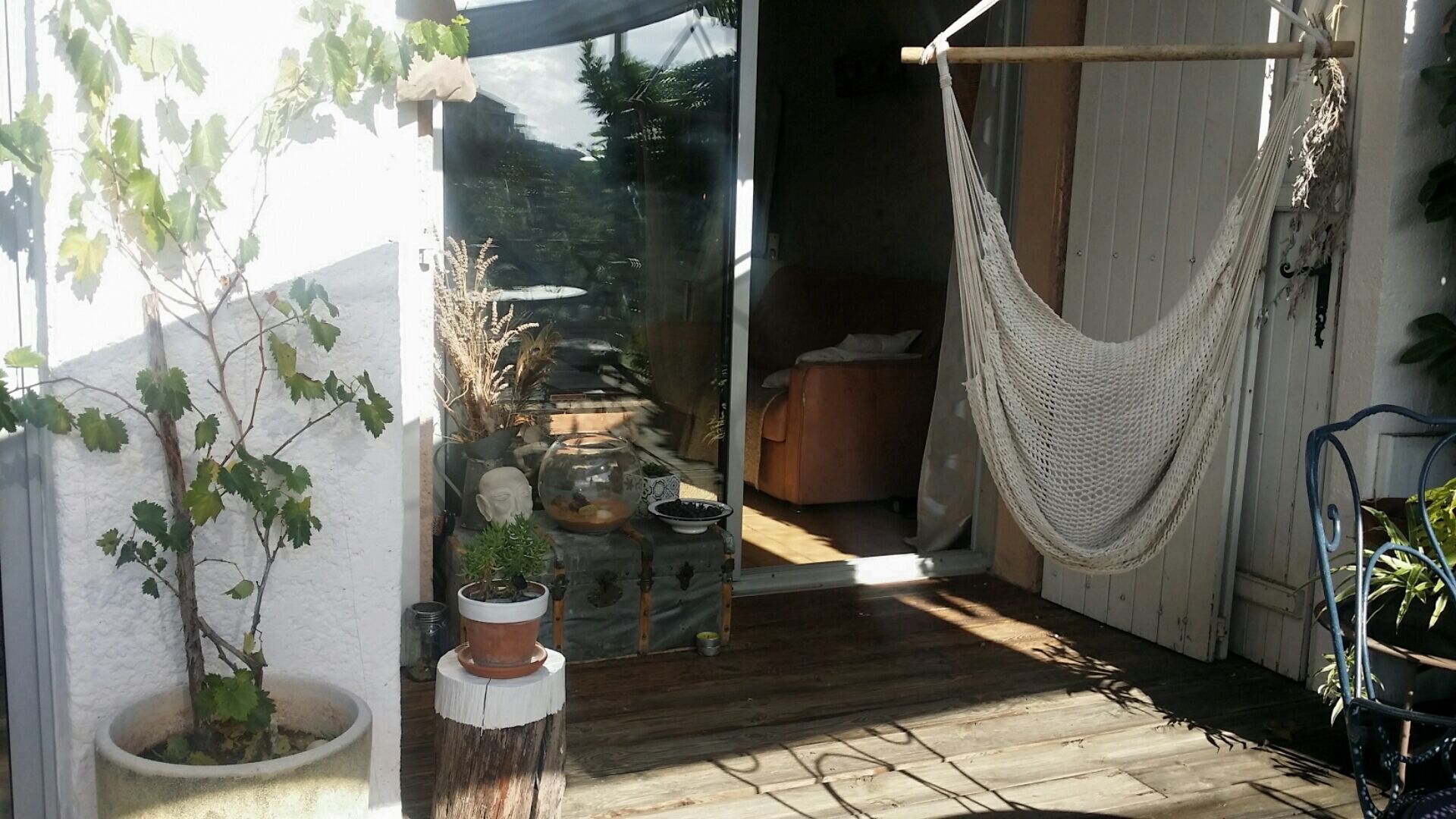 A wooden deck with a hammock, a potted plant, and a rustic outdoor seating area.