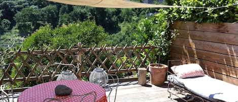 A wooden deck with a table and chairs, a bench, and potted plants.