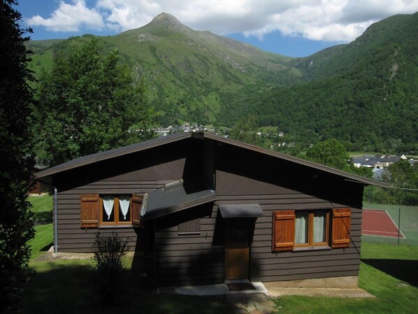 Une cabane avec un toit en pente, des volets en bois et un petit porche.