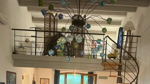 Een ruime woonruimte met een hoge plafond, een spiltrap en uitzicht op de omgeving.