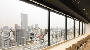A conference room with a city view, large windows, and a long table with chairs.