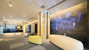A modern lobby with a seating area, a reception desk, and a wall with a projection.