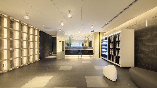A modern hotel lobby with a reception desk, seating area, and a display of magazines.