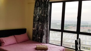 Una habitación con cama, ventana y vista panorámica de la ciudad, además de cortina.