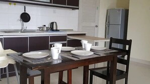 Una cocina con una mesa de comedor lista para cuatro personas, un refrigerador y una estufa.