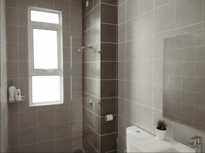 A bathroom with a shower, toilet, and sink. There is a window and a mirror on the wall. - Damansara Foresta Ctmp Home by SYNC (Batu Caves)