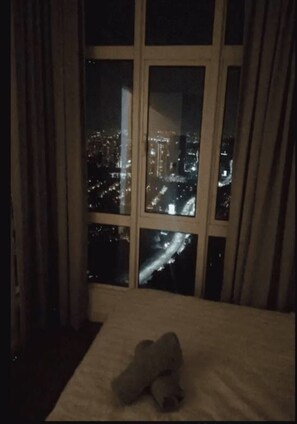A room with a large window overlooking a cityscape at night. - Damansara Foresta Ctmp Home by SYNC (Batu Caves)