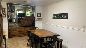Ein Essbereich mit einem Holztisch, vier Stühlen und einem 'WELCOME'-Schild an der Wand.
