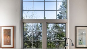 A wooden desk with a bench, a window with a view of trees, and two framed pictures on the wall. - A Quiet Riverside Cottage with 2 Fireplaces (Crousetown)