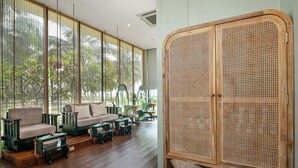 A room with a rattan wardrobe, a sofa set, and a view through large windows. - Sunset Sanato Resort & Villas (Phu Quoc)