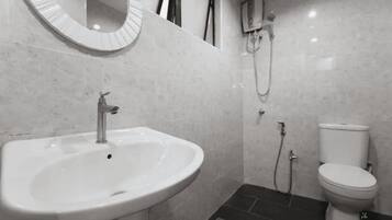 A bathroom with a sink, mirror, toilet, and shower.
