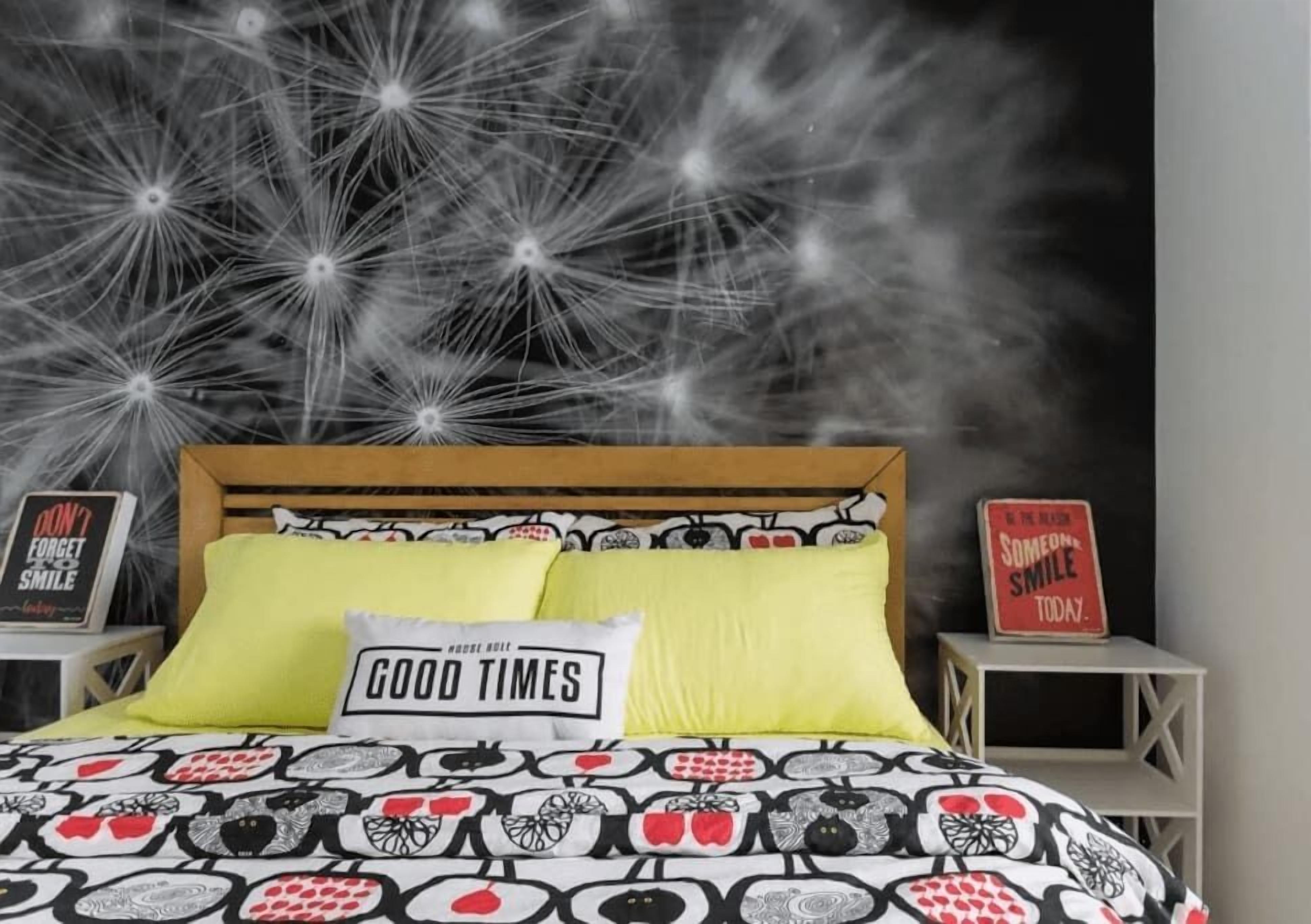 A bedroom with a bed, pillows, and two bedside tables with motivational signs.