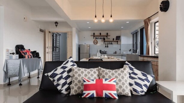 A modern living room with a black sofa, patterned cushions, and a Union Jack pillow. - Desa Kiara Cozy Condo by SYNC (Kuala Lumpur)