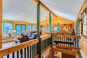 Ein Holzinterieur mit Balkon, einer Couch, einem Esstisch und einer Küchenzeile.