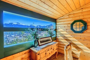 Eine Holzhütte mit einem großen Fenster, einem Holzschrank und einem Stuhl.