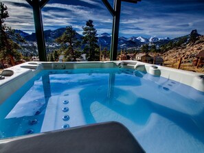 A hot tub with a mountain view, surrounded by trees and a wooden structure. - Park Entrance Lodge RMNP Views! Gas FirePit, HTub, Billiards, Indoor BBCourt (Estes Park)