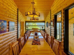 Ein langer Holztisch mit Stühlen, einer Chandelierleuchtre und gerahmten Bildern an den Wänden.