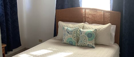 A bedroom with a bed, a ceiling fan, and a window with curtains.