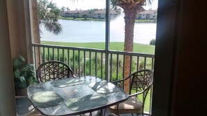 Ein Balkon mit Tisch und Stühlen, der auf ein Gewässer und Gebäude blickt.