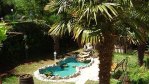 Un patio trasero con un pequeño estanque, una palmera y una terraza de madera.