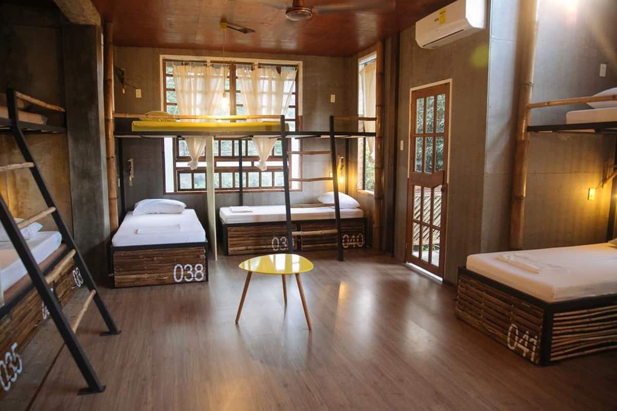 A room with bunk beds, a small round table, and a window with curtains.