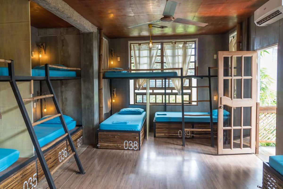A compact room with bunk beds, a ceiling fan, and a window with curtains.