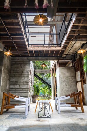An interior space with a high ceiling, exposed beams, and a central table with chairs. - The Flying Fish Hostel (Dumaguete)
