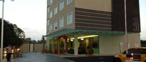 Ein Hotel mit Glasfassade, rotem Markisen und einem gepflasterten Zugangsweg.