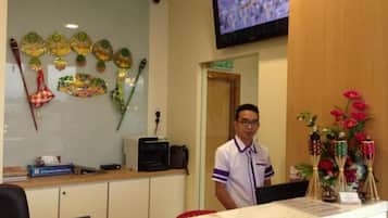 A reception area with a desk, a television mounted on the wall, and decorative items on the wall and counter.