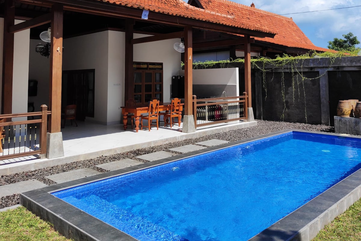 Une maison avec une piscine, une terrasse en bois et un toit recouvert de tuiles.