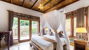 A spacious bedroom with a large bed, a wooden headboard, and a canopy. - Bali Royal Heritage Villas (Keroboken Kelod)
